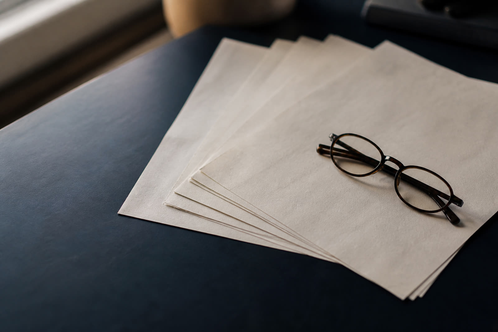 Documents disposés en éventail avec des lunettes sur une table sombre